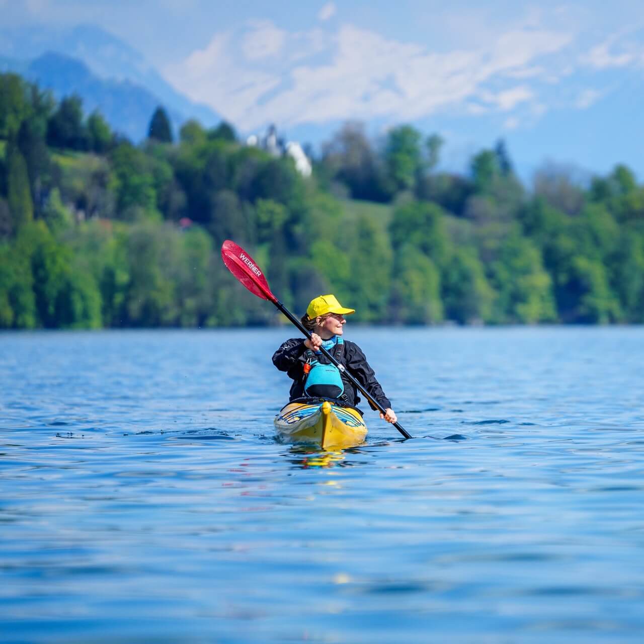 Frau fährt mit einem gelben Kajak und rotem Paddel auf dem Wasser