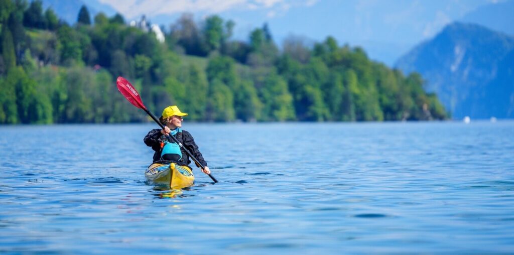 Frau fährt mit einem gelben Kajak und rotem Paddel auf dem Wasser